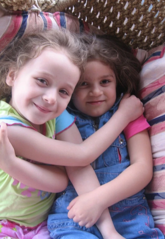 two little girls that are sitting together on pillows