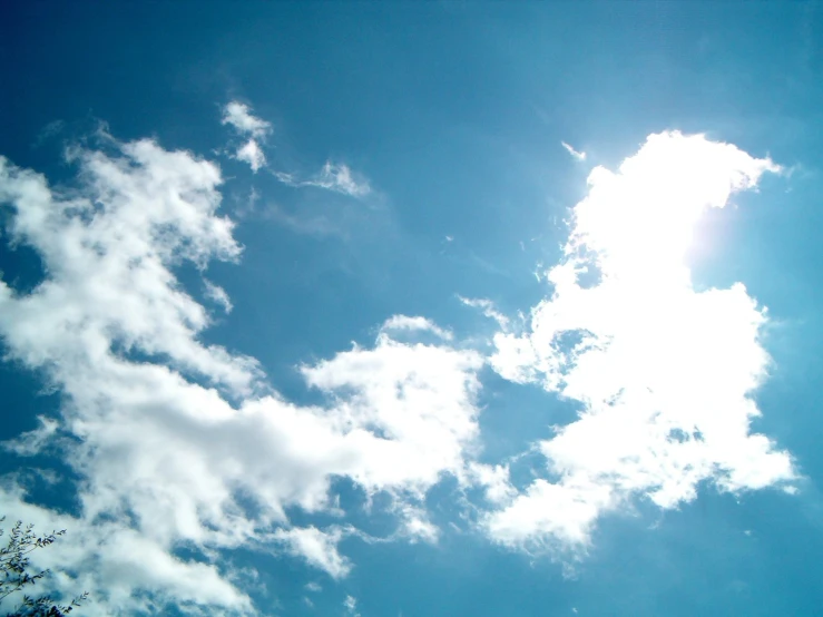 a clear blue sky with clouds and an airplane in the foreground