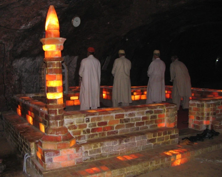five monks in an underground cave with orange lights