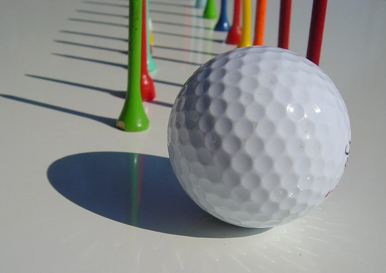 a golf ball and several colorful tees in front of it