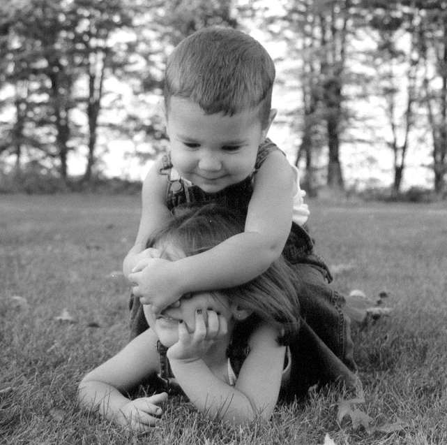 a small boy playing with another little girl in the grass