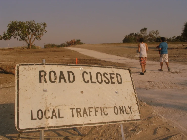 a road closed sign next to a dirt path