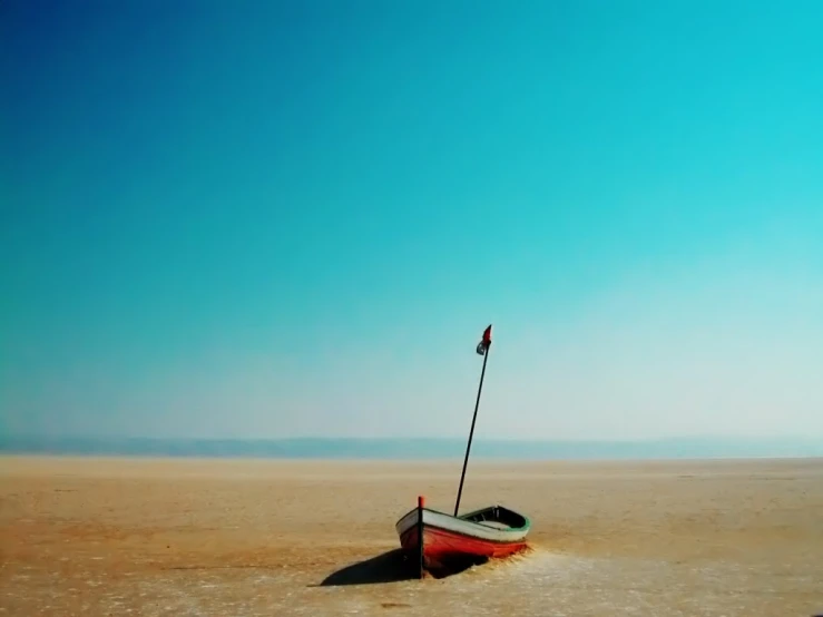 a small boat sits alone on the beach