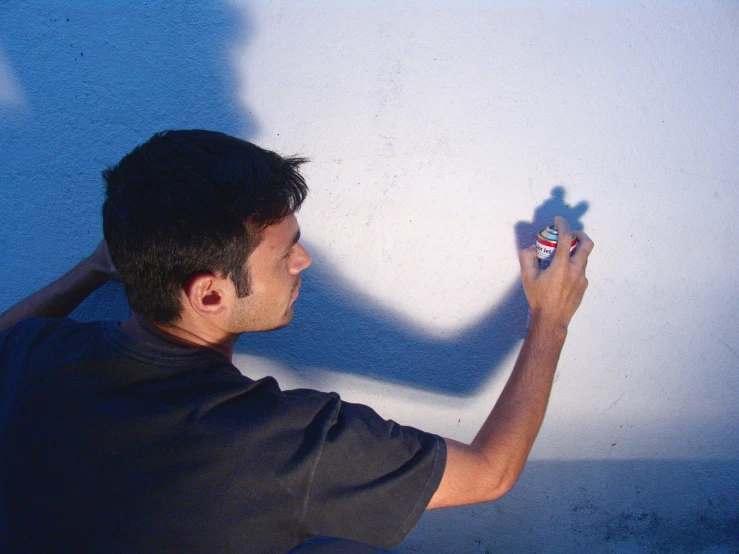 the shadows of a man holding an object in his hand