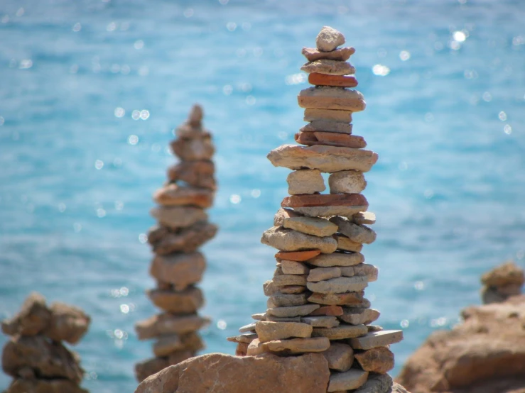 three piles of rocks on the beach by the ocean