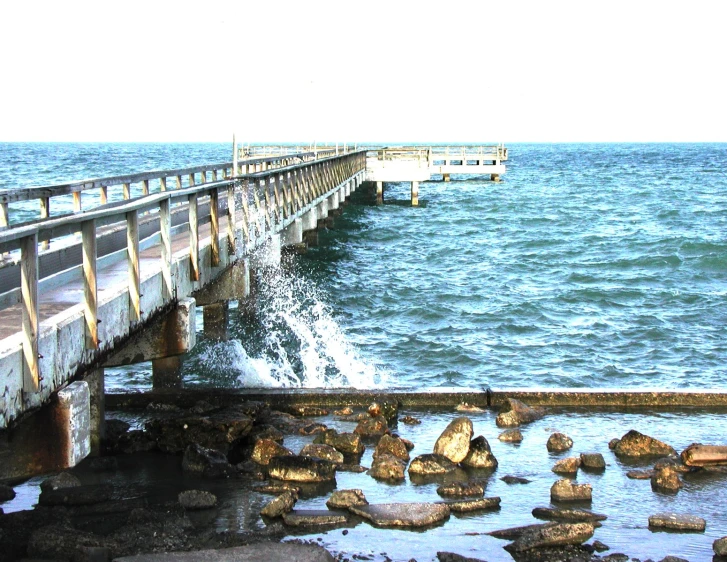 the pier is surrounded by large rocks in front of water