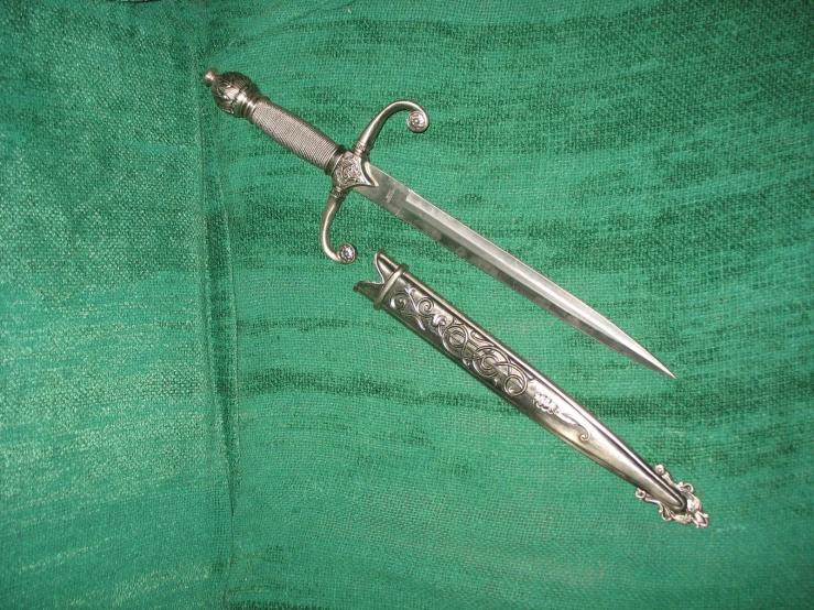 the dagger and other old silver items lie on the cloth