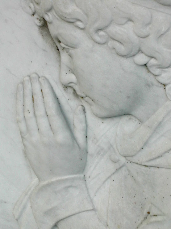 a statue of a person wearing gloves and praying