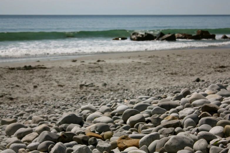 a bunch of rocks are in the sand by the beach