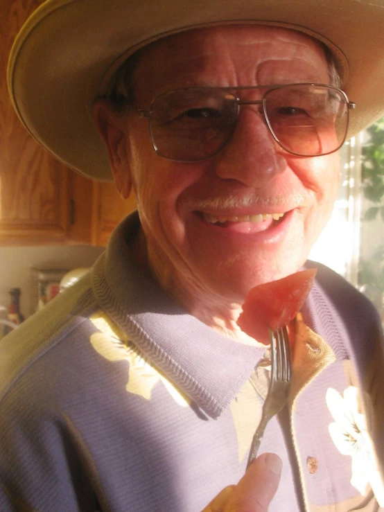 the man smiles while eating food off of a fork