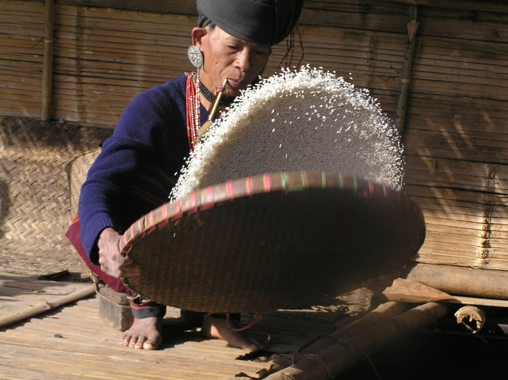 the woman is weaving a large item in her hands