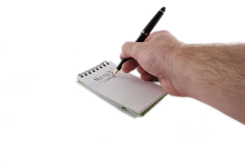 a hand holding a pen while writing on a note pad