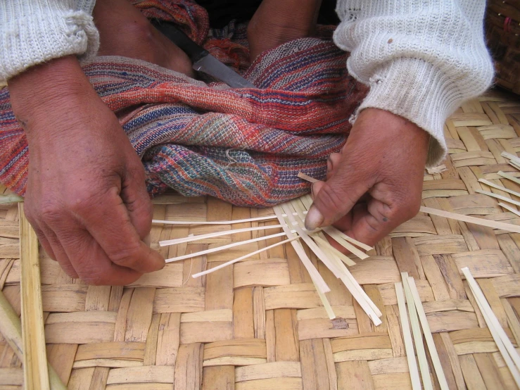 someone holding a pair of bamboo skewers and tying them together