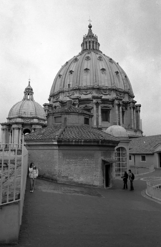 people stand near a large domed building with many windows