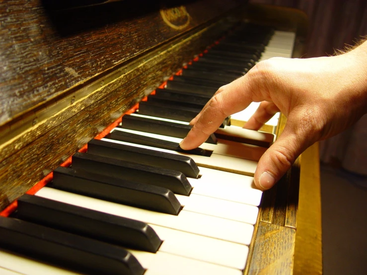a man's hand touching an open piano keys