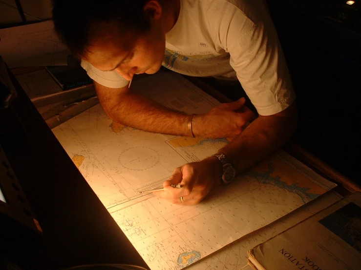 a man in a white t - shirt is writing on a piece of paper