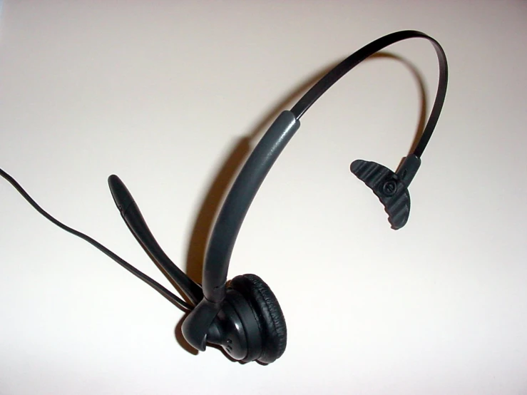 a black headset with two ears attached is sitting upright on a white surface