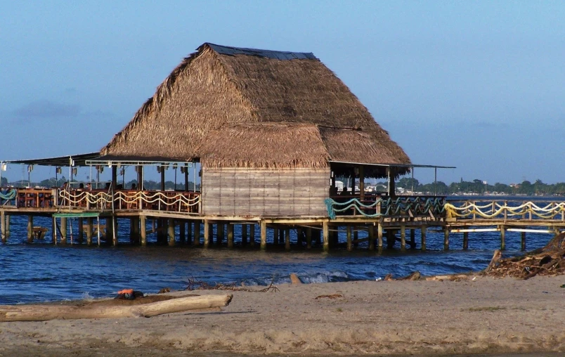 an ocean side house with thatched roof near the water