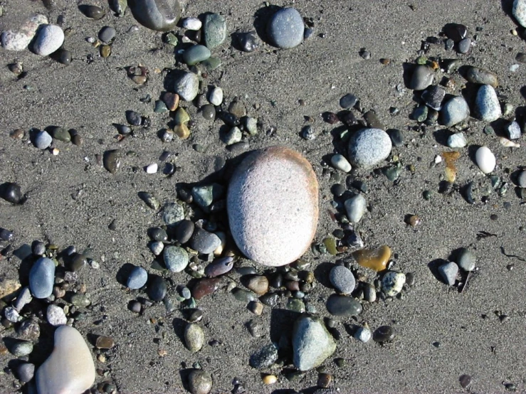 a white rock sitting on top of some black sand