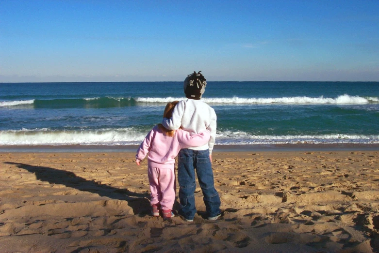 the father and daughter are standing together looking out at the ocean