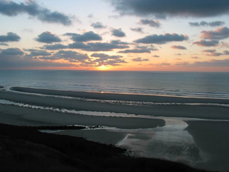 the sun sets over some beach sand and water