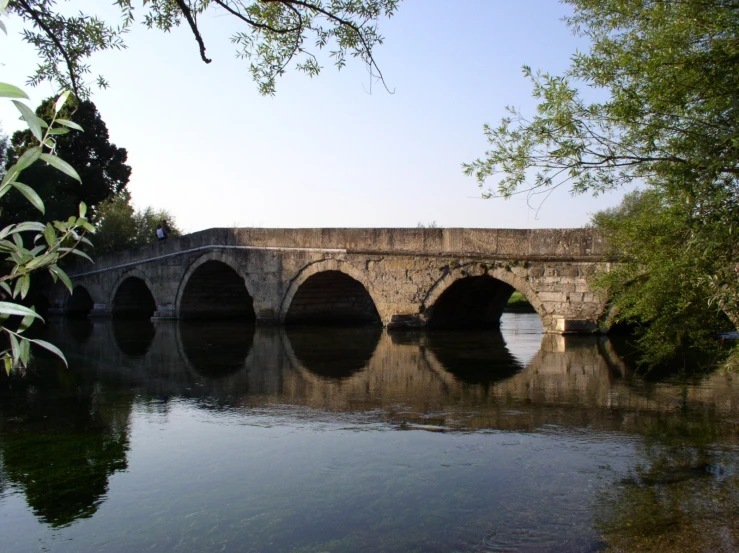 an old stone bridge spanning a river near trees