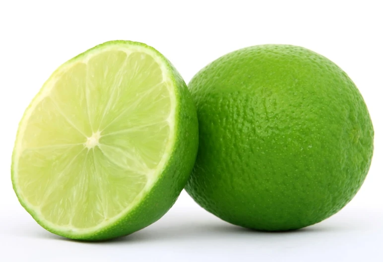 two limes are cut into halves on a white background