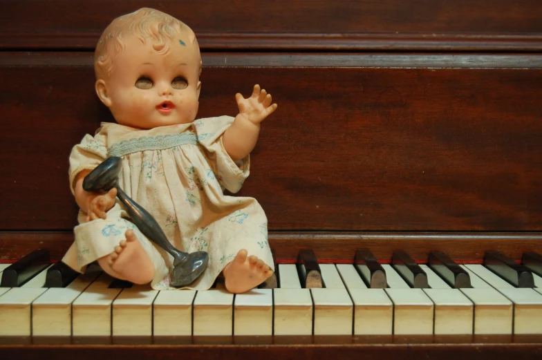 baby doll sitting on piano keys with a cell phone