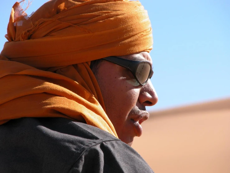 the man is wearing sunglasses and has his head wrapped in a scarf