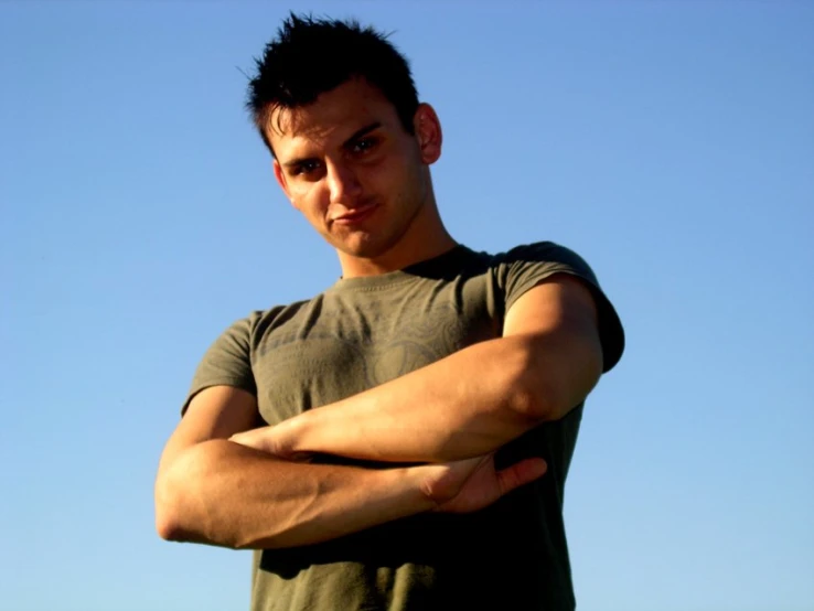 a man standing with his arms crossed in a dark t - shirt
