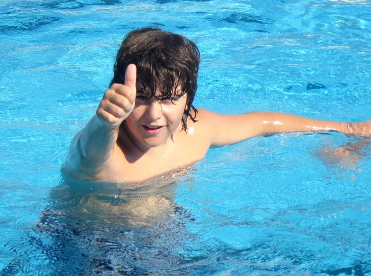 a child giving the thumbs up while swimming in a pool
