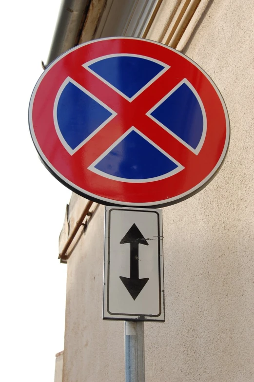 a red blue and white street sign with a black arrow pointing in opposite directions