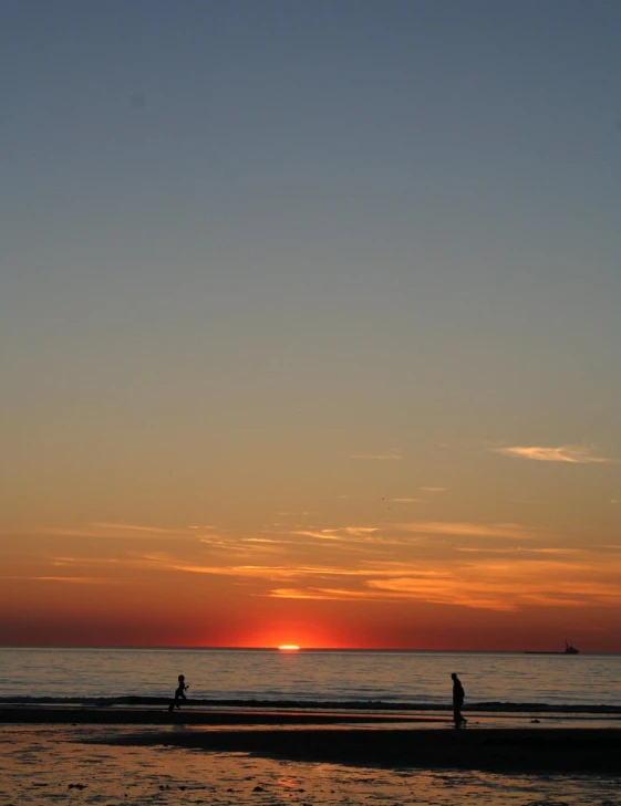 two people on the beach in front of a sunset