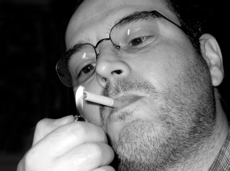 a man wearing glasses and smoking a cigarette