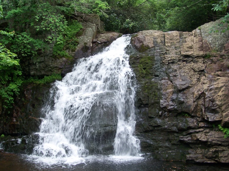 water cascading down a rocky waterfall surrounded by greenery