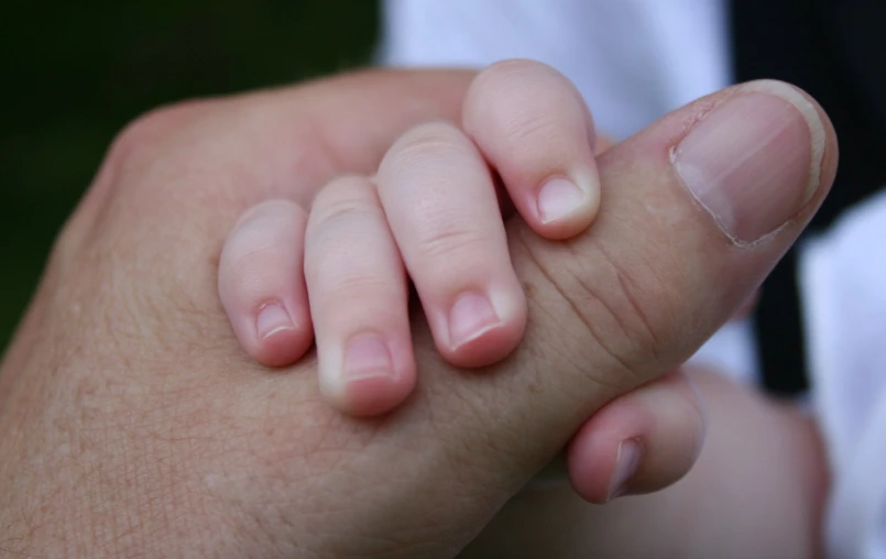 a person holds a baby's hand while it rests on its other