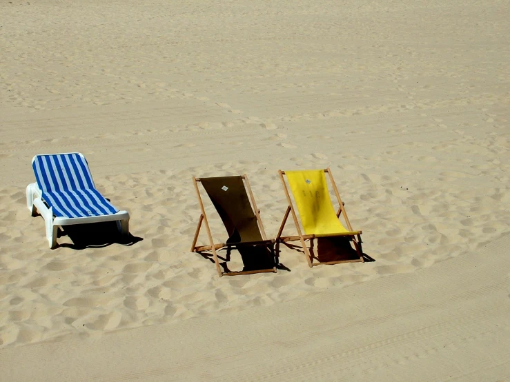 three chairs are sitting in the sand on the beach