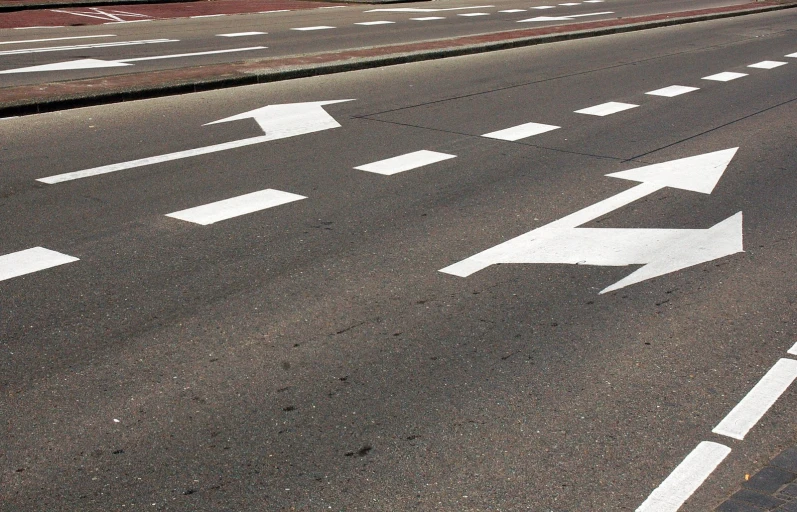 an empty street and traffic signs with arrows painted on it