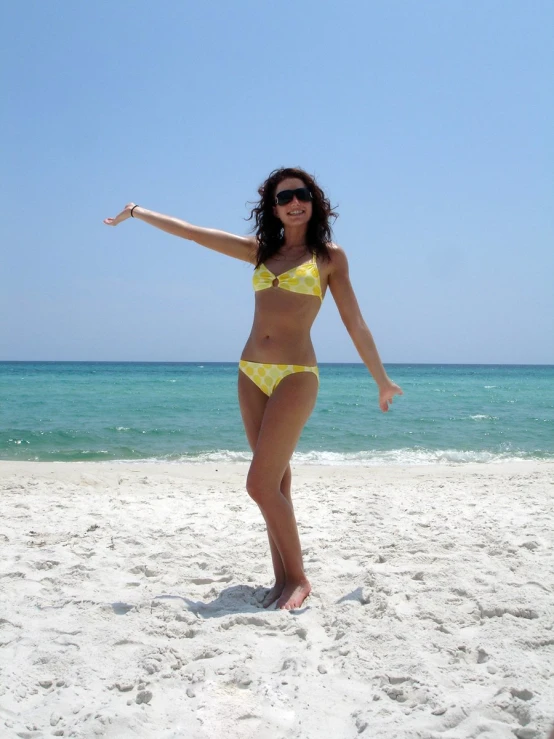 a woman in a yellow bikini plays with her frisbee on the beach