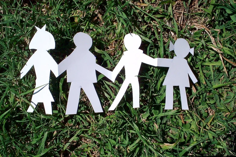 a cut out of paper of people holding hands on a grass field