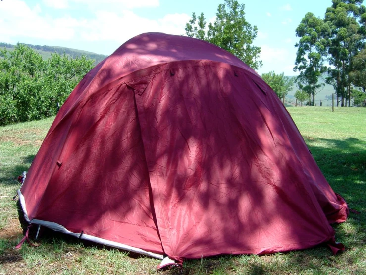 a large red tent in the middle of a grassy field