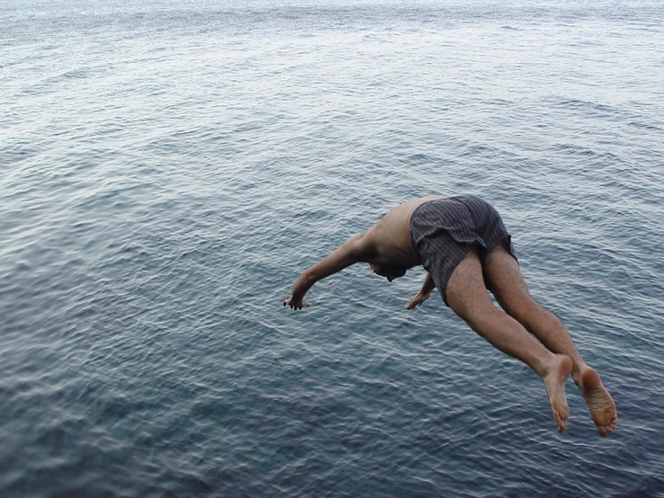 a man is dives into the water from a dock