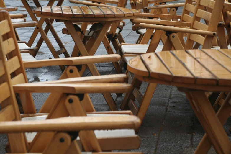 there are many wooden tables and chairs on the sidewalk