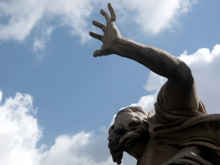 a statue of the hand of liberty is in front of the clouds