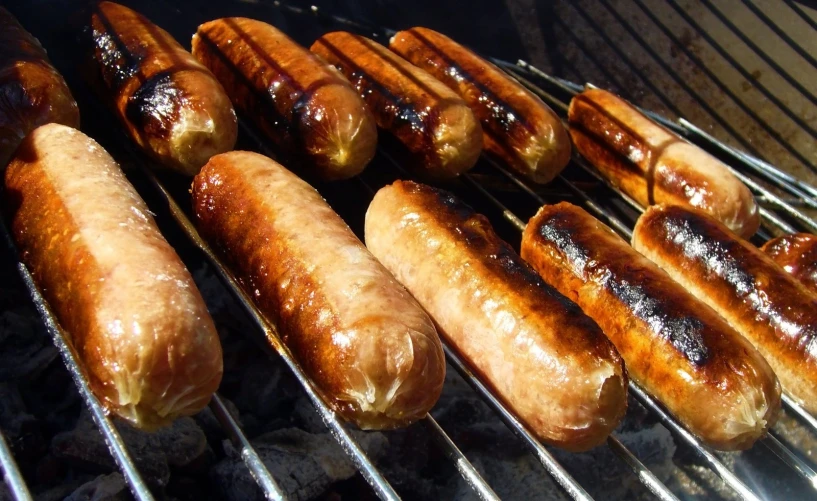  dogs and sausages cooking on an outdoor grill