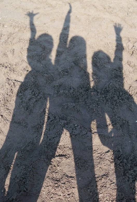 a couple of people are casting their shadow on the sand