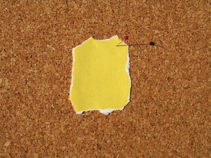 a piece of yellow paper pinned to a cork bulletin board