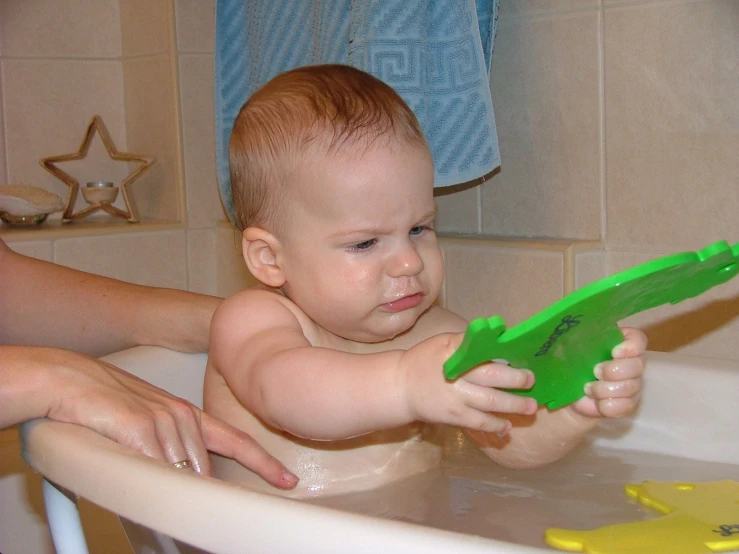 a woman washing the baby in a tub with a tooth brush