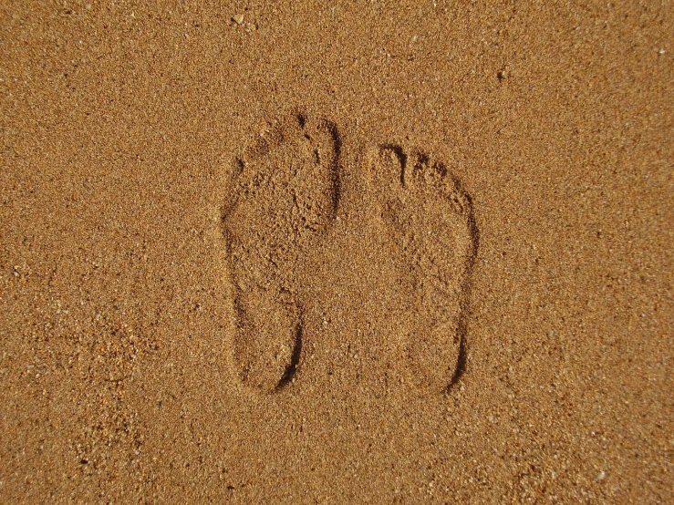 a pair of feet in the sand at the beach