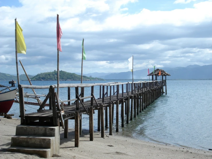 a boat on a dock at the ocean with three flags